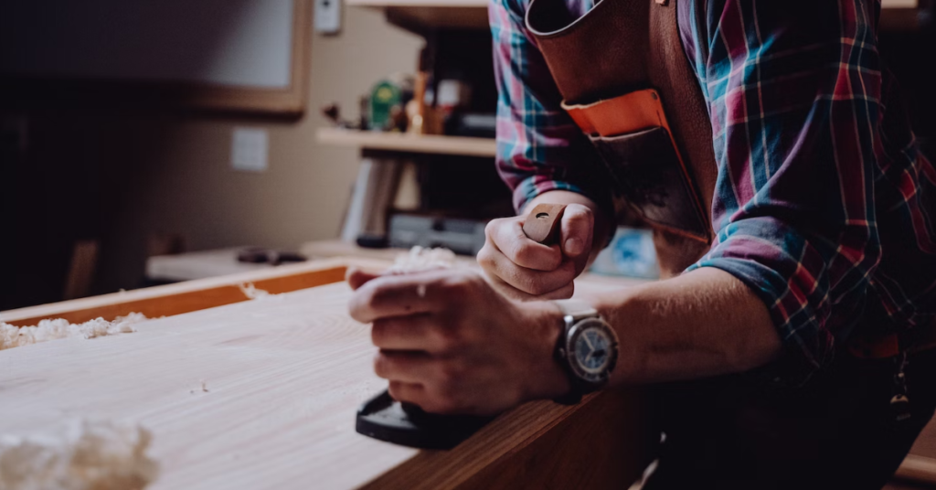 A man ensuring a smooth surface for his wooden table.