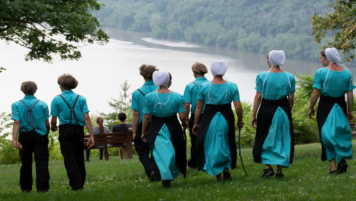 Amish men and women walking down the lake.