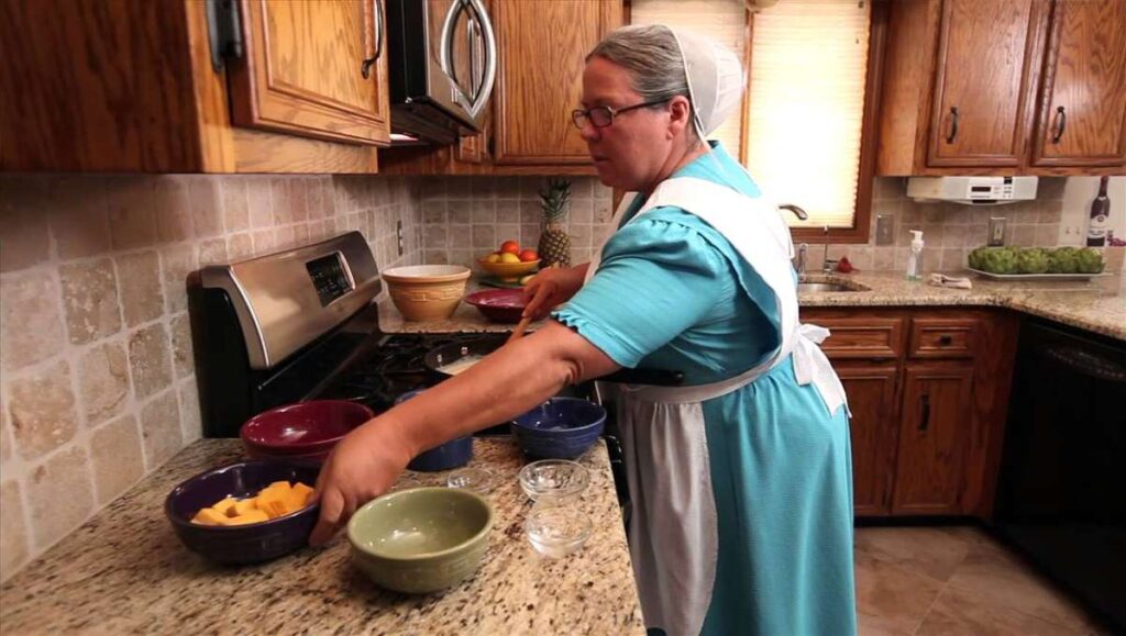 An Amish woman cooking in the kitchen.