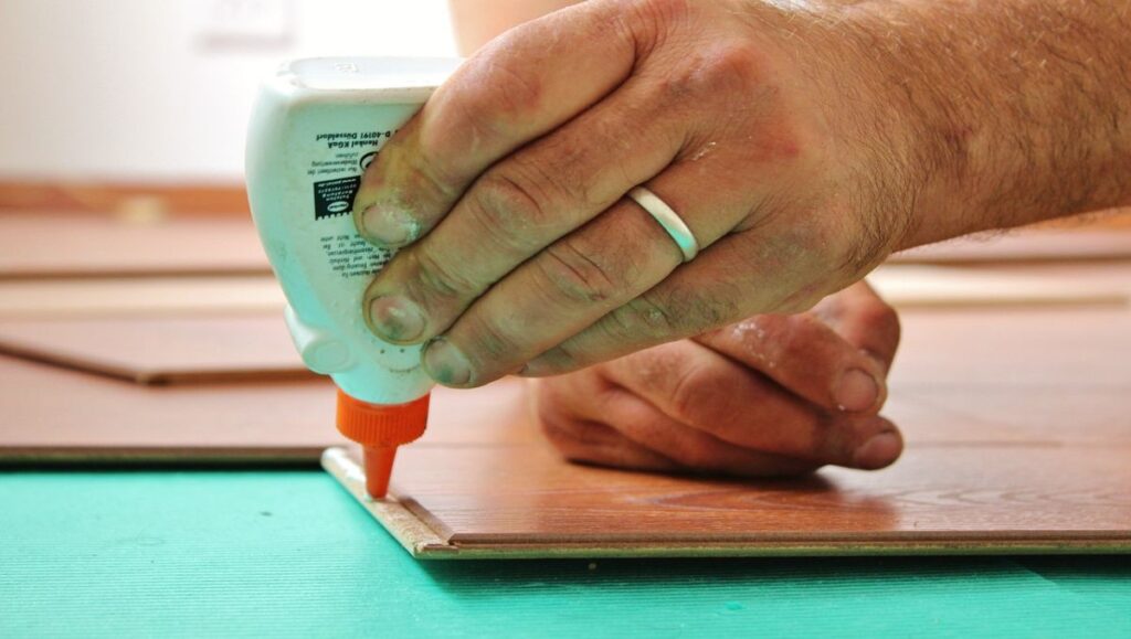 A hand applying glue to the wood.
