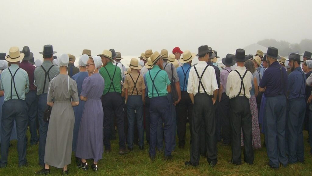 Amish men and women standing on the field.