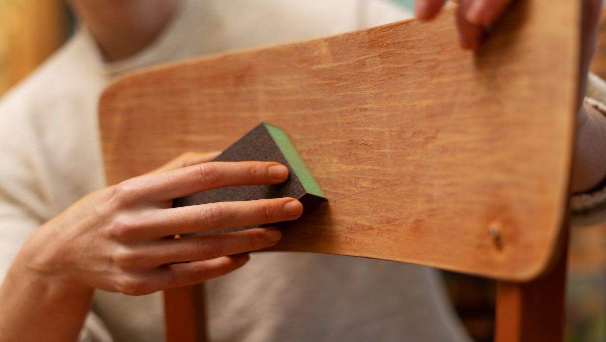 Man sanding furniture for scratch repair