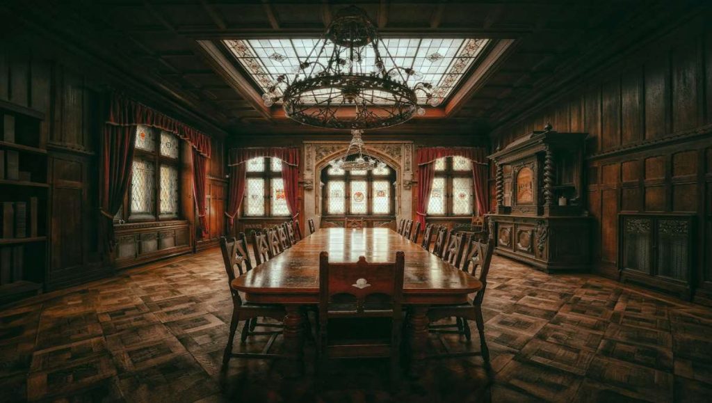 A dining room with old furniture including chairs, table, and cabinet