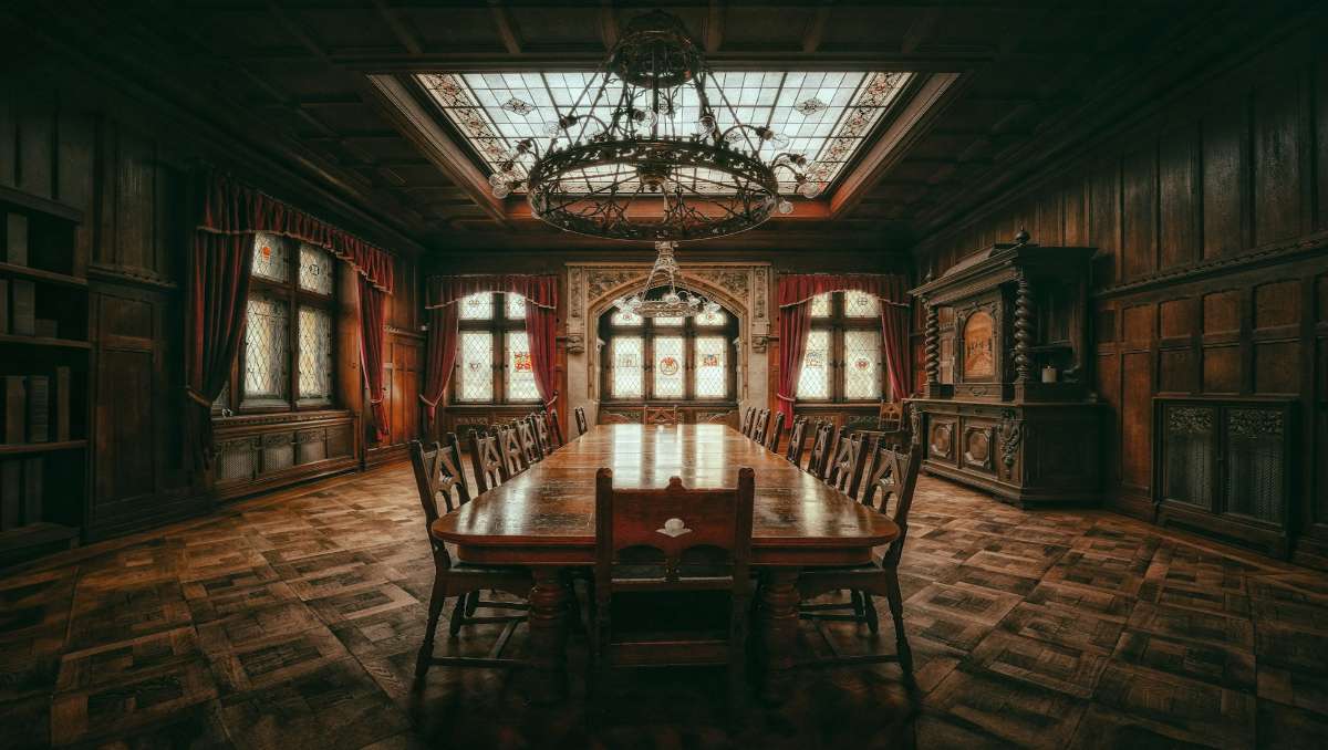 A dining room with old furniture including chairs, table, and cabinet