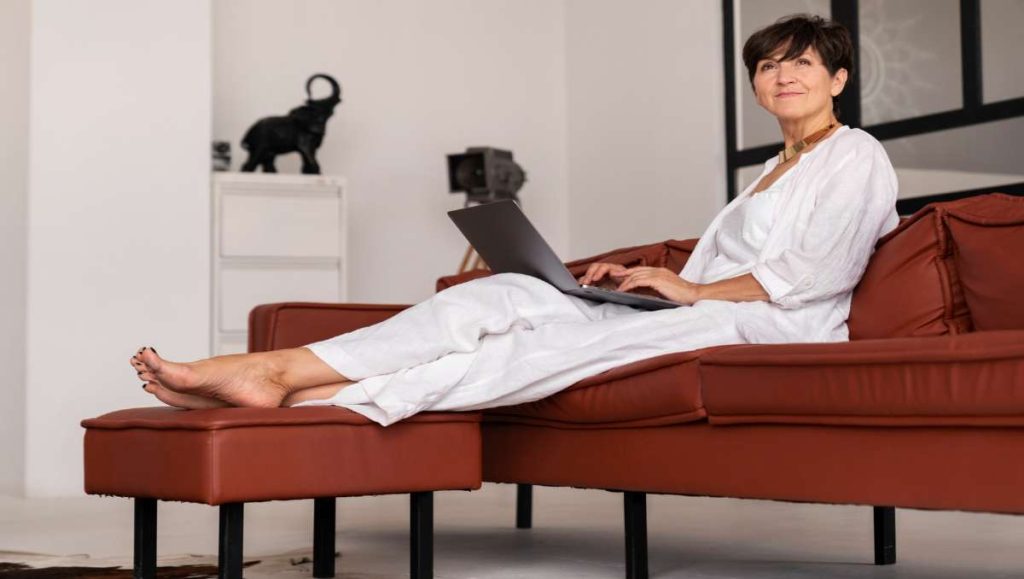 furniture you put your feet on Woman sitting on the couch while resting her feet on the footrest