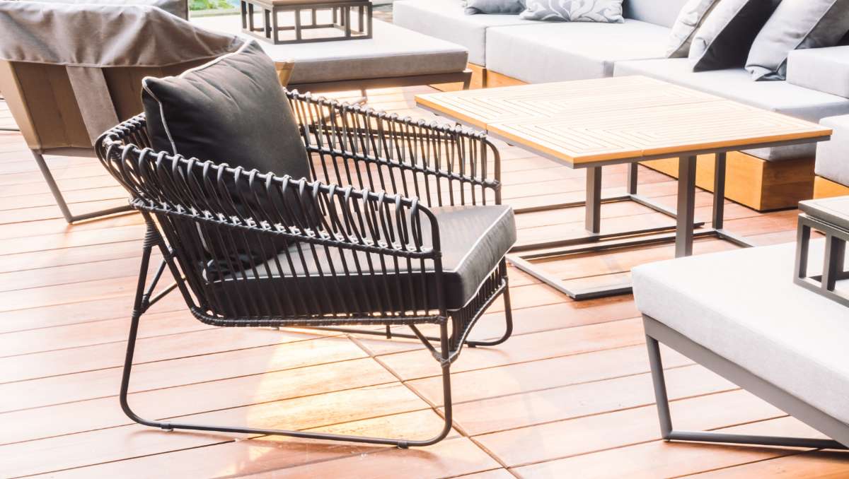 Outdoor furniture including black metal chair, wooden table, and gray couch